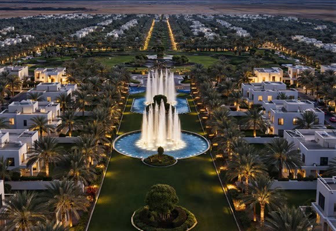 Lit fountain and landscaped boulevard at dusk within the township